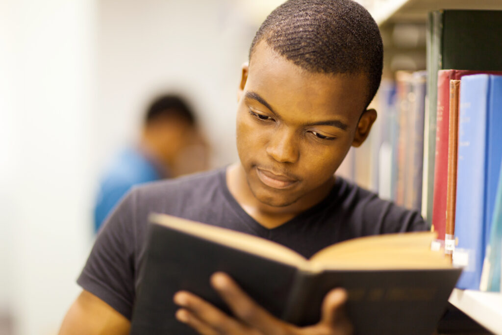 young man reading in library to represent black education